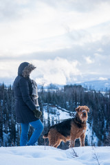 Woman and Airdale Terrier in Winter Mountains