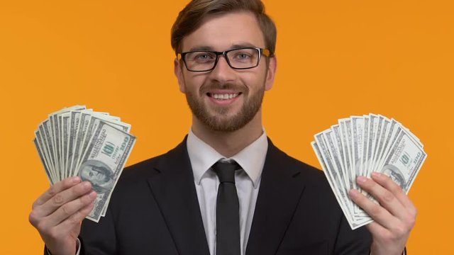 Handsome man showing full hands of dollars, decent wages, investment, close-up