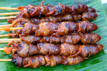 Thai street vendor sells grilled chicken hearts at street food market in island Koh Phangan, Thailand. Closeup