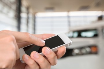 Hand holds phone and car.