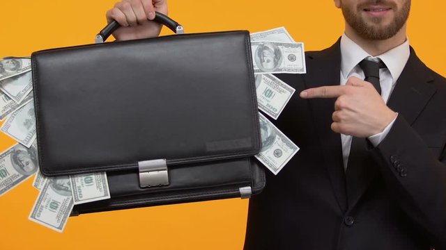 Man pointing at money sticking out from his case, additional income, capital