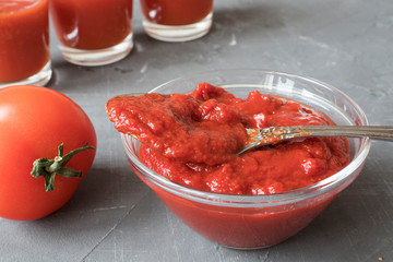 tomato juice in cups and tomato paste on a concrete background, selective focus