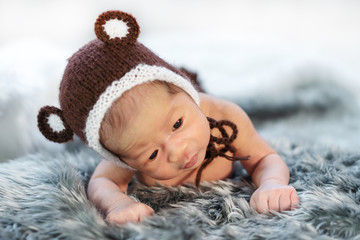 newborn baby in bear hat on fur bed