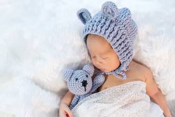 newborn baby in bear hat sleeping on fur bed