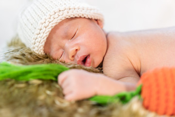 newborn baby in bunny costume sleeping on fur bed