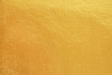 Gold paint on rough cement wall texture.