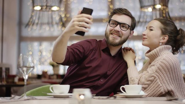 Adult man takes selfie with his girlfriend while she is hugging him and stroking his hair