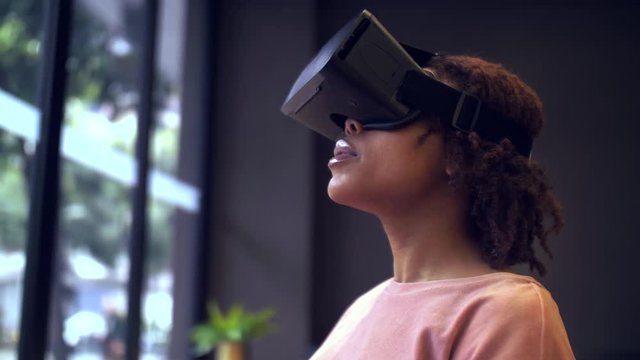 Close up of one pretty young African woman wear VR headset indoor, experience breathtaking virtual reality movie game,  black young woman shocked emotion, the concept of VR technology 4k clip