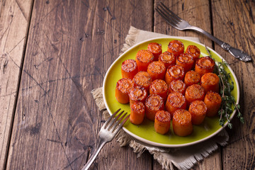 Delicious baked carrots with spices and thyme on a wooden table