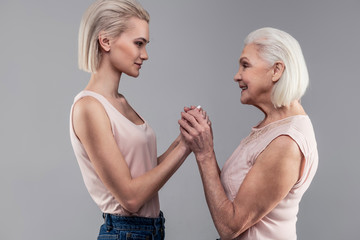 Smiling old lady with grey hair gently touching hands