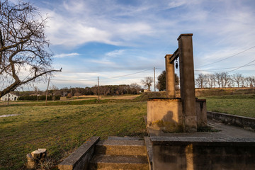 Fototapeta na wymiar Old water well on a countryside green landscape