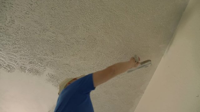 A man troweling out ceiling texture on a home remodel