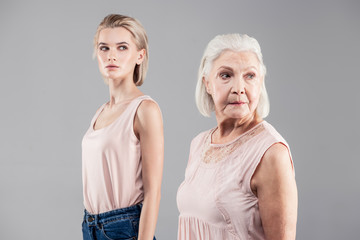 Old grey-haired woman taking look behind while her daughter