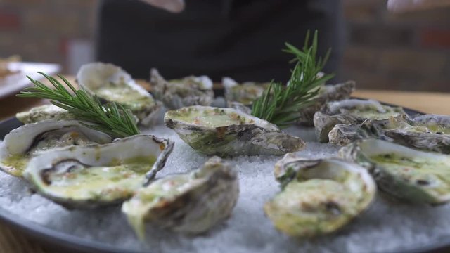 Food design styling concept. Chef cook decorating oysters with rosemary on plate. Food decotation in seafood restaurant. Seafood dishes in luxury restaurant.