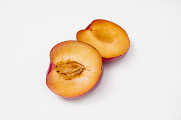 Sliced red blue plum isolated on white background one cut in two halves.