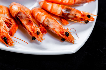 Grilled prawns with soy sauce, lemon and herbs. Royal delicious and beautiful shrimp on black background. Flatley. Food background