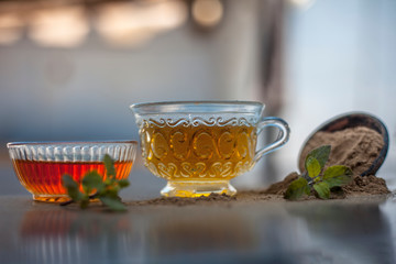 Ayurvedic herb brahmi or Waterhyssop with its tea  in a small transparent glass bottle along with its powder and a bowl of honey on wooden surface.