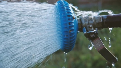 Sparkling water flowing from a shower head in a garden in summer in slow motion