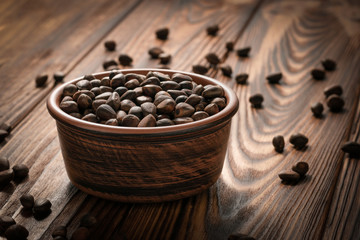 Inshell pine nuts in a clay bowl on a wooden table