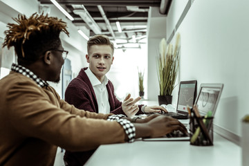 Light-haired man in burgundy jacket explaining his idea to interested colleague