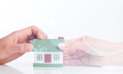 Building, mortgage, real estate and property concept - close up of hands with house model