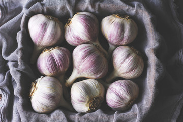 moody photo of unpeeled purple garlic wrapped in a purple napkin taken using natural light