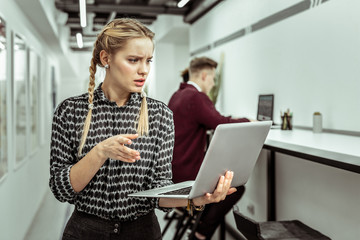 Confused woman with two braids looking nonplussed while dealing with work aspects