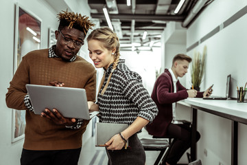 Attentive African American man and long-haired woman looking on laptop screen