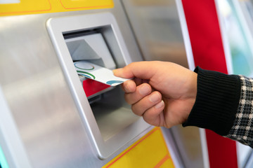 male hand businessman inserts credit card into the ATM and withdraws money