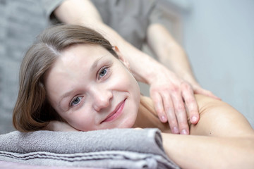 Obraz na płótnie Canvas Beautiful young woman is receiving a massage at a massage salon