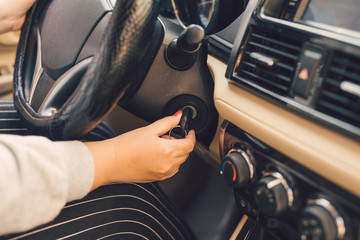 Woman hand put key into the ignition and starts the car engine