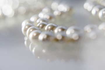 A necklace of pearls lying on white glass 