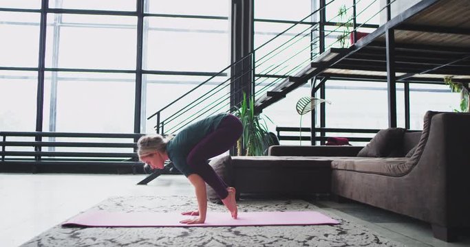 Hard yoga poses at home lady practicing in the morning headstand and bend at home in a stylish living room with a sophisticated design around.