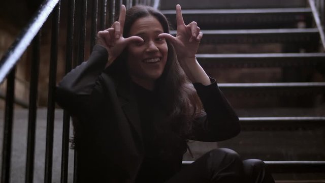 Medium comedic shot of an attractive woman making a double handed loser gesture 