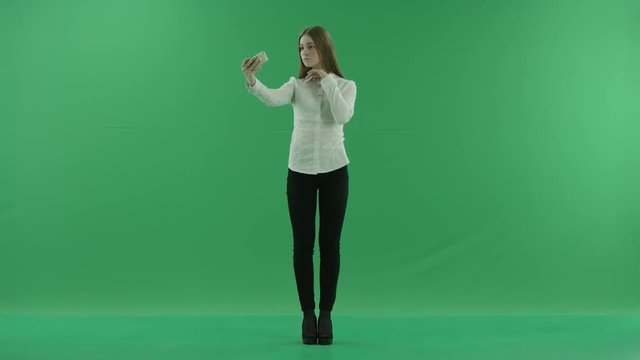 young business woman is taking selfies on the green screen standing front