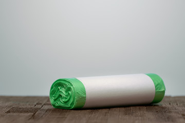 Roll green eco garbage bag with copy space isolated on brown wood background.
