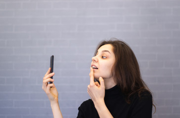 Young smiling woman through the camera looks at her teeth