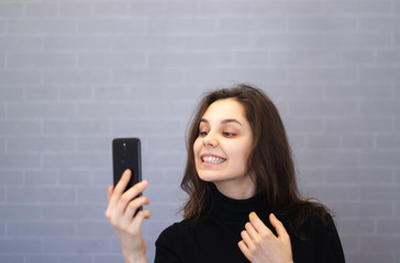 Naklejka premium Young smiling woman through the camera looks at her teeth