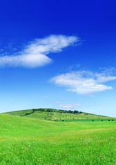 Fototapeta premium Idyllic view, green hills and blue sky with white clouds