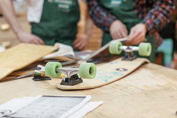 Two unknown male carpenters make a skateboard on an exclusive order. Concept hobby for youth and handmade