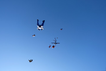 Skydivers are in the blue sky.