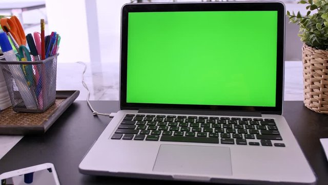 4K Green screen of laptop computer set on working space in cozy office, Zoom out shot.