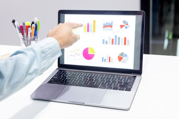 Businessman workspace laptop with coffee cup ,computer screen graphics and chart at office room