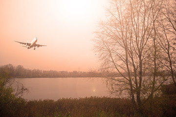 Fototapeta na wymiar Airliner over the lake in cloudy weather. Sunset.