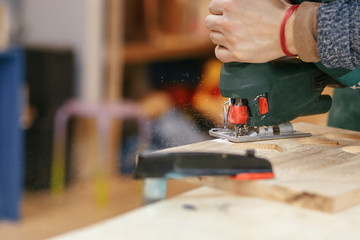 Hands of a professional woodworker make a souvenir kitchen board with a tool with a cutter. Concept of profession carpenter builder