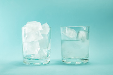 Сoncept of global warming. Melting pieces of ice in a glass on a blue background.