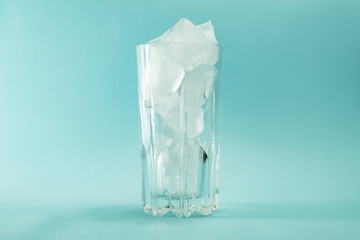 Сoncept of global warming. Melting pieces of ice in a glass on a blue background.