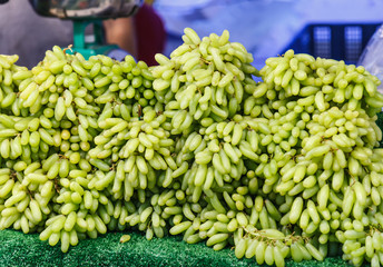 fresh natural wild tropical cluster of sweet Asian green raw ripe grapes berry fruit from garden on farmer market stall. Seasonal Food Nutrition, Summer grape fruit on street food market booth concept