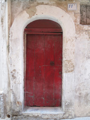 Fototapeta na wymiar red wooden door with a doorknob of an old house in Italy Puglia