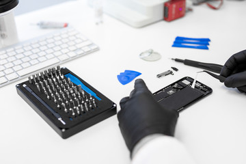 Hands of repair technician fixing mobile phone in service center